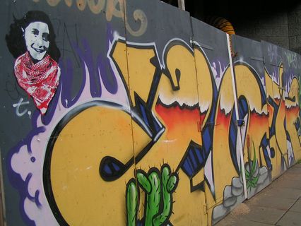 Gros graff sur une palissade avec Anne Frank en Kefiey au premier plan