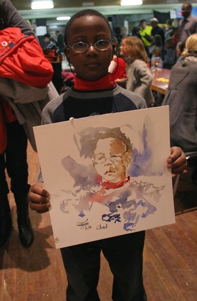 un enfant a lunettes montre son portrait à l'aquarelle