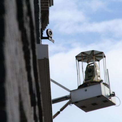 Un théodolite flou et un petit rond noir net le long d'une facade