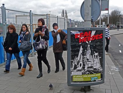 quatre femmes marchent dans la rue et passent à coté d'une affiche pour un spectacle